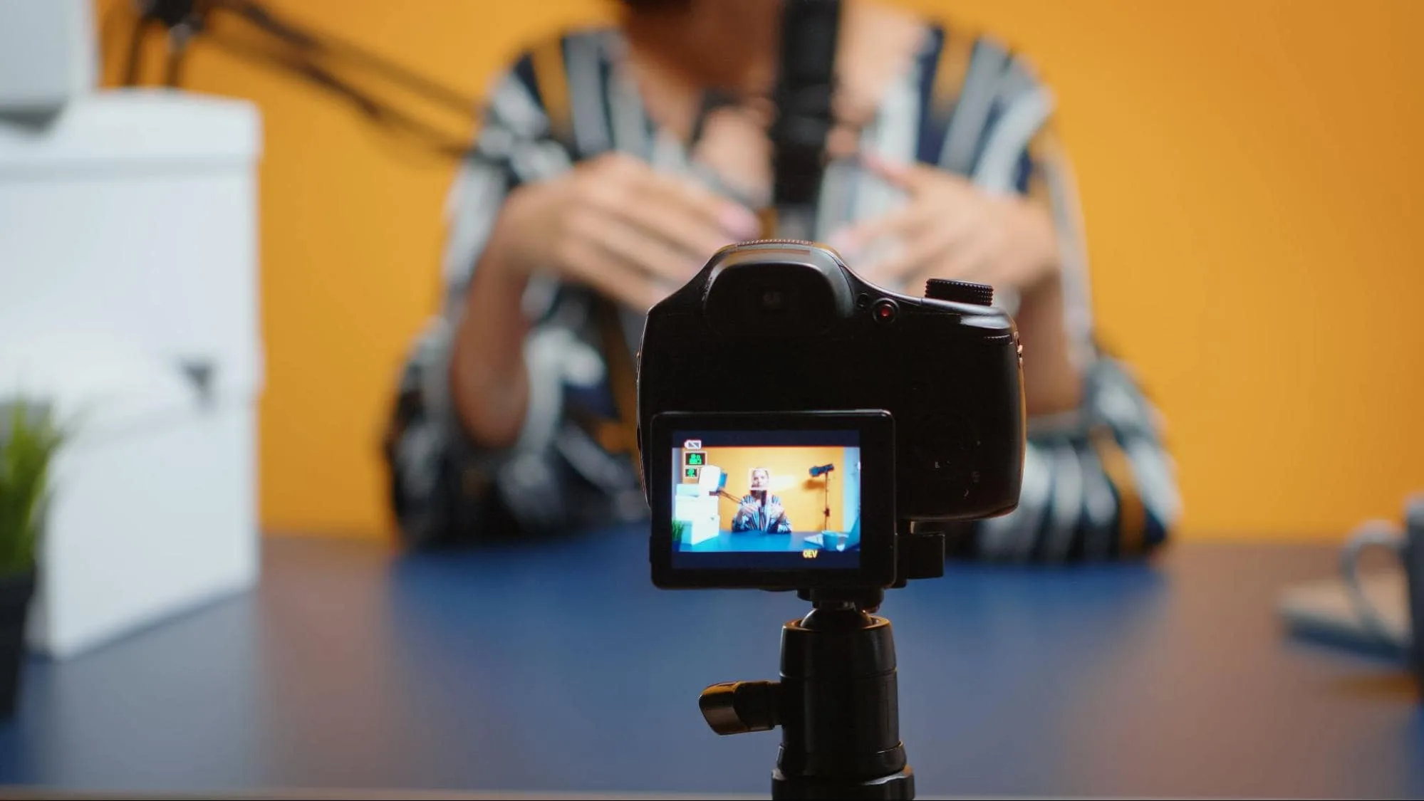 A female business professional recording a podcast and filming herself on a digital camera.
