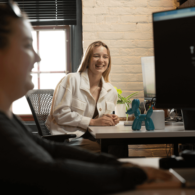 Two Tower Marketing employees laughing at their open-space office in Lancaster, PA